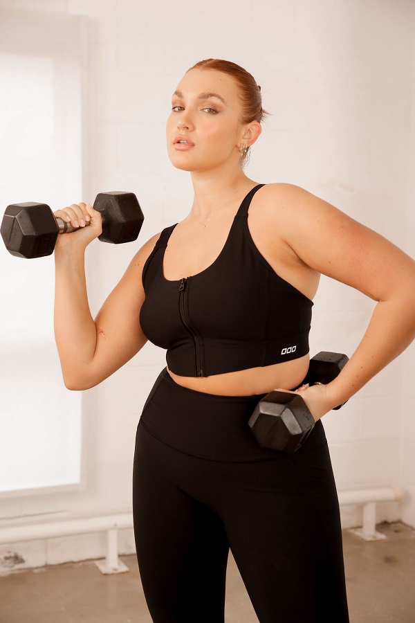 woman wearing black ultimate excel zip front closure sports bra while lifting weights
