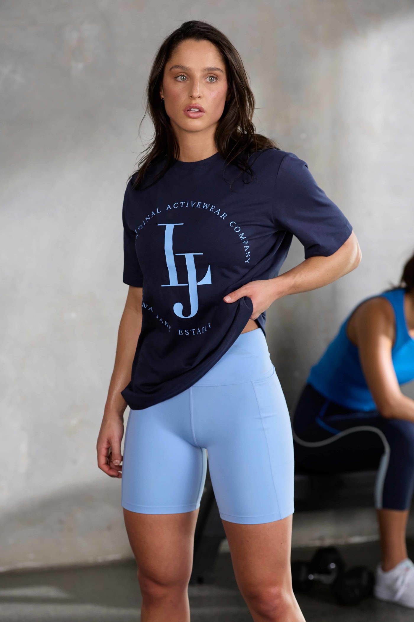 Front image of a model wearing a light blue Lorna Jane activewear set and a French Navy Lorna Jane branded top.