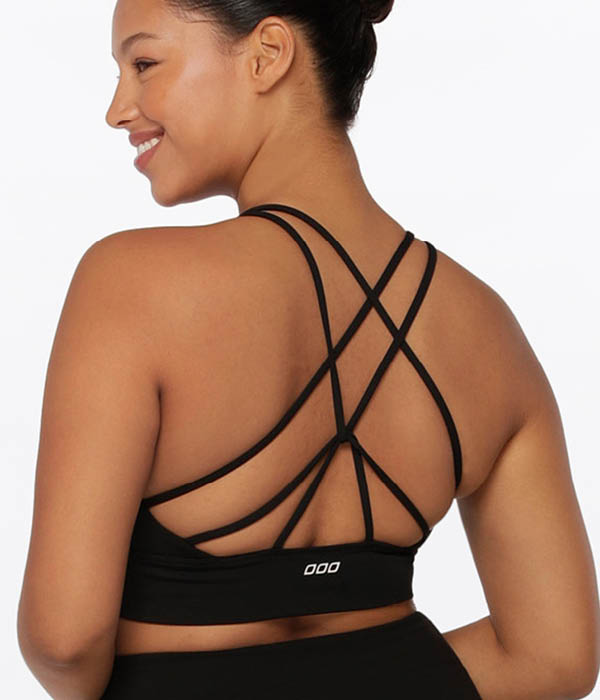 Woman wearing lorna jane lotus longline all day support black strappy back sports bra and matching black lotus leggings