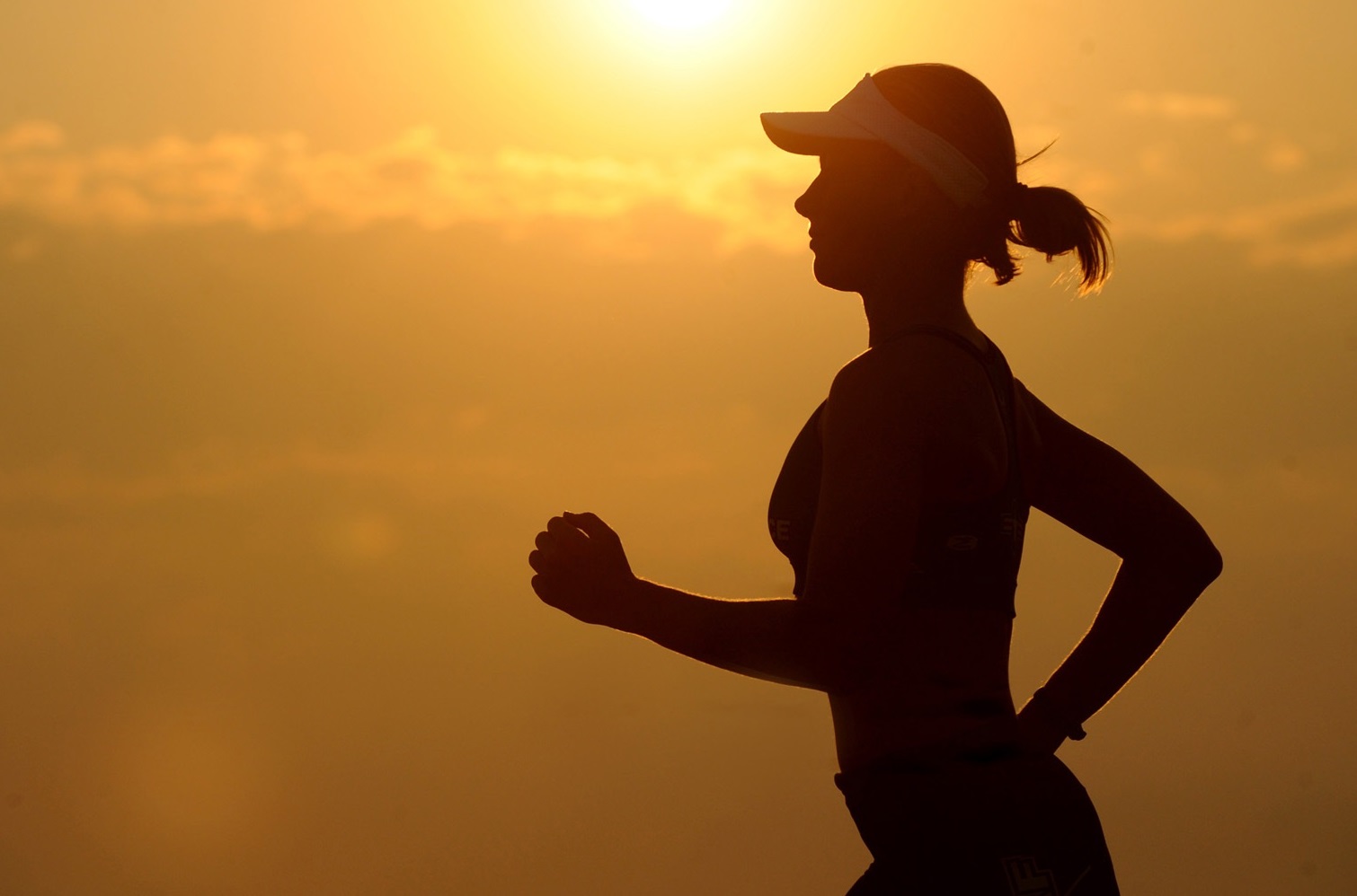 Woman running at sunset wearing activewear and a visor